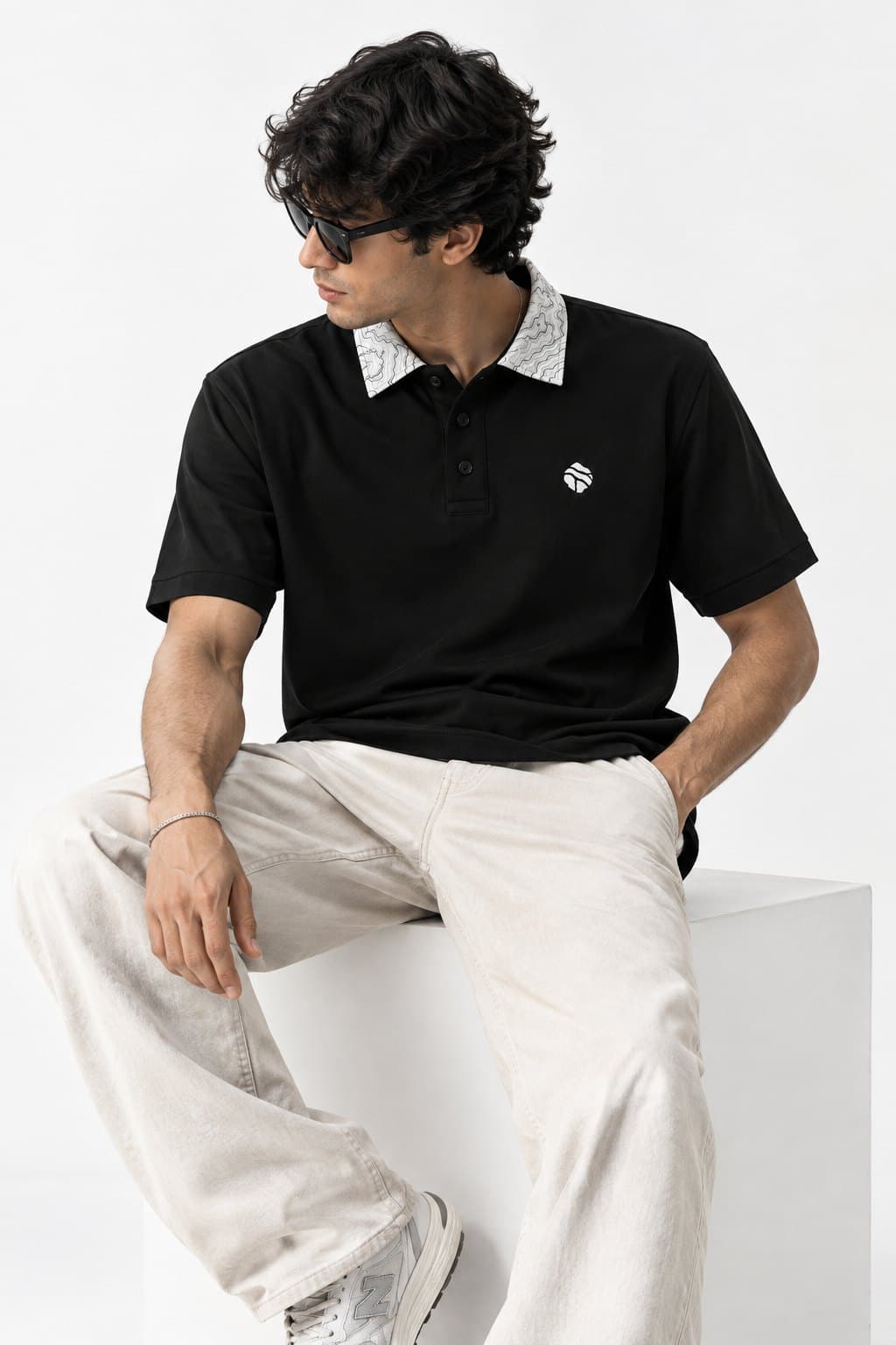 Model seated, wearing the black Land Form polo